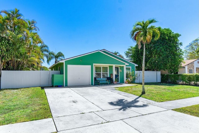 view of front facade with concrete driveway, a front lawn, a garage, and fence