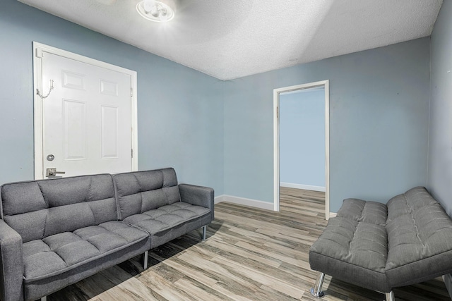 living room with light wood-style floors, baseboards, and a textured ceiling