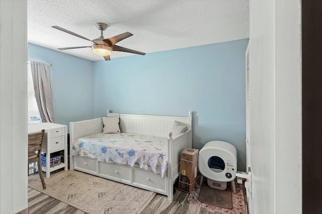 bedroom featuring a textured ceiling, ceiling fan, and wood finished floors