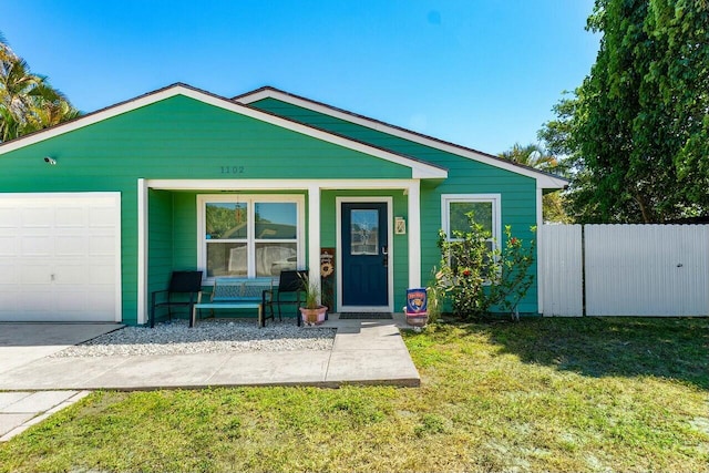 view of front of home featuring a garage, covered porch, a front yard, and fence