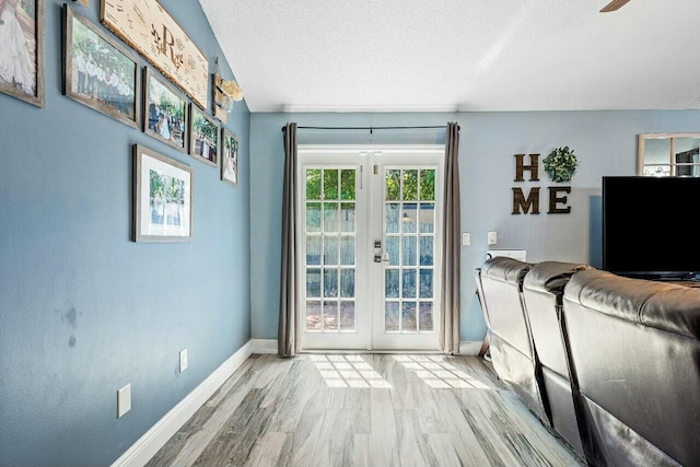 unfurnished living room featuring french doors, a textured ceiling, baseboards, and wood finished floors