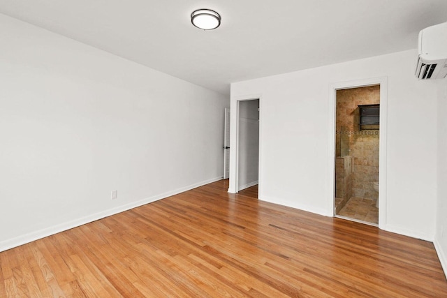 empty room with light wood-style flooring, baseboards, and an AC wall unit