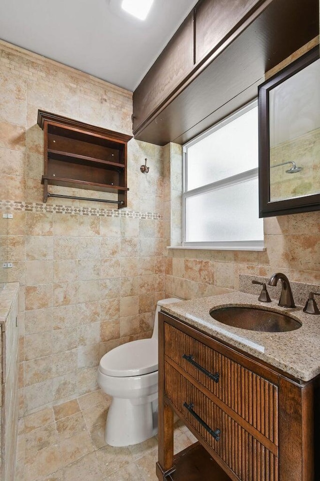 bathroom with tile walls, toilet, and vanity