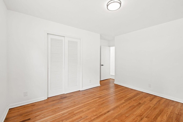 unfurnished bedroom with a closet, baseboards, and light wood finished floors