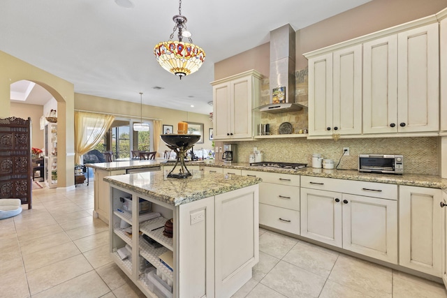 kitchen with a peninsula, tasteful backsplash, arched walkways, open shelves, and wall chimney range hood