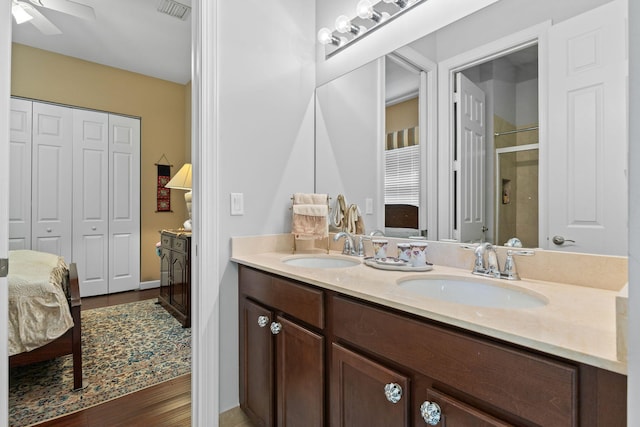 ensuite bathroom featuring double vanity, a sink, a shower stall, and visible vents