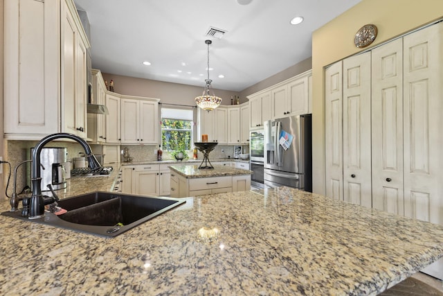 kitchen featuring a sink, tasteful backsplash, appliances with stainless steel finishes, a center island, and visible vents