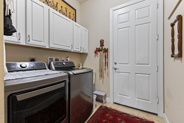 clothes washing area with light tile patterned flooring, baseboards, washer and dryer, and cabinet space