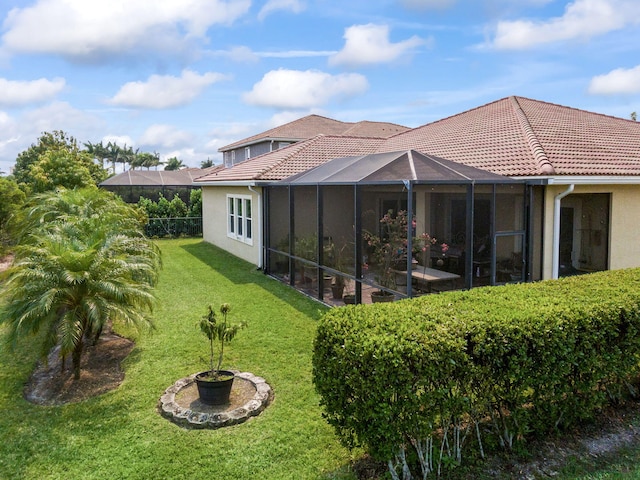 rear view of house with a tiled roof, stucco siding, and a yard
