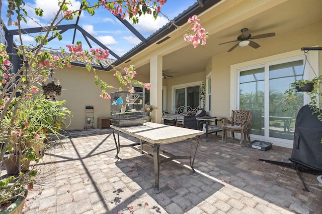 view of patio with a ceiling fan and glass enclosure