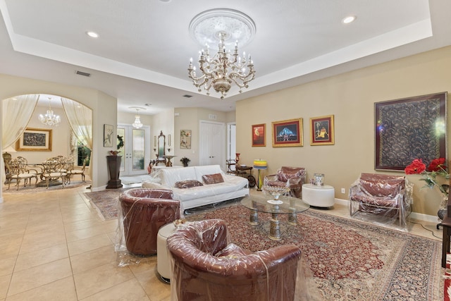 living area featuring a raised ceiling, light tile patterned floors, and a chandelier
