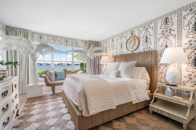 bedroom featuring a water view and wallpapered walls