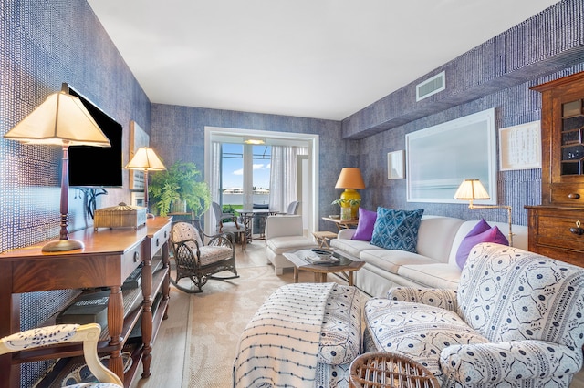 living room featuring wood finished floors, visible vents, and wallpapered walls