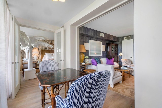 dining area featuring light wood finished floors, visible vents, and wallpapered walls