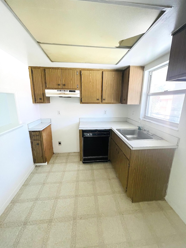 kitchen with black dishwasher, light floors, light countertops, brown cabinetry, and under cabinet range hood