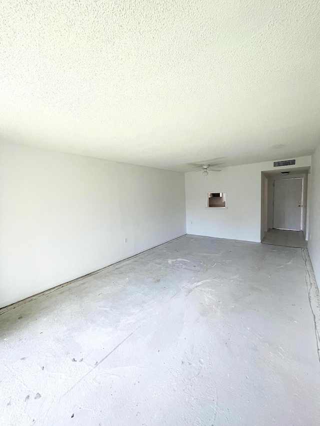 spare room with visible vents, unfinished concrete flooring, a textured ceiling, and a wall mounted air conditioner