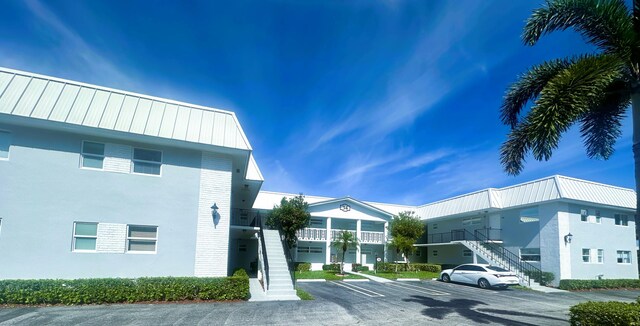 view of property featuring stairs and uncovered parking