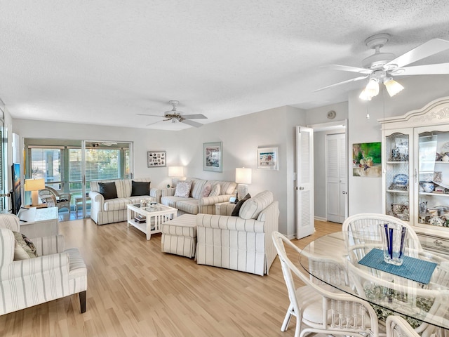 living area with a textured ceiling, a ceiling fan, and light wood-style floors