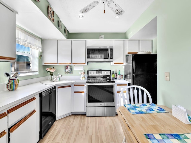 kitchen featuring a sink, black appliances, light countertops, and white cabinetry