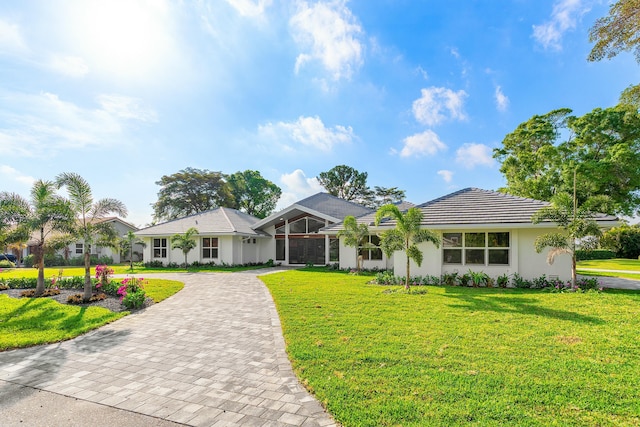 view of front of property featuring a front lawn, decorative driveway, a tile roof, and stucco siding