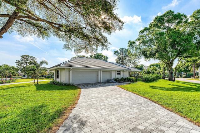 ranch-style home with a tiled roof, a front yard, stucco siding, decorative driveway, and an attached garage