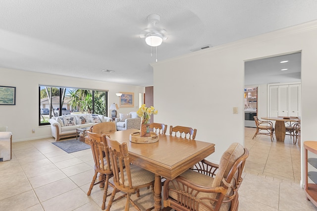 dining space with light tile patterned flooring, visible vents, a textured ceiling, and ornamental molding