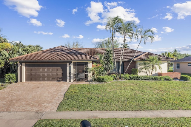 view of front of home with a tiled roof, a front yard, stucco siding, decorative driveway, and an attached garage