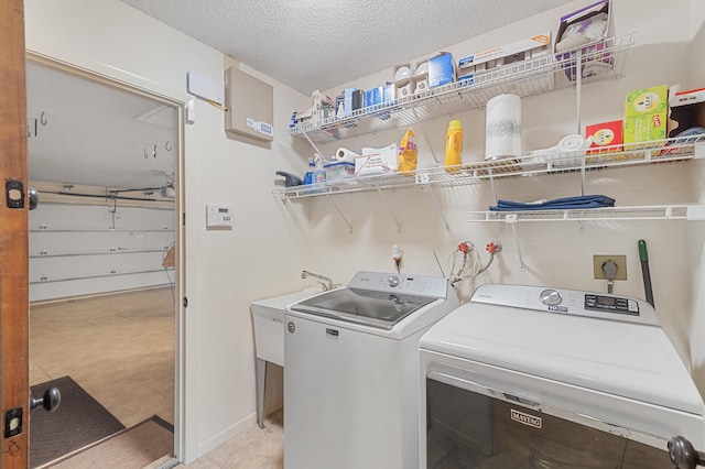 washroom featuring laundry area, a sink, a garage, a textured ceiling, and independent washer and dryer