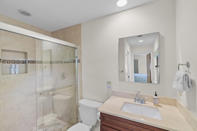 full bathroom with toilet, a stall shower, vanity, and a textured ceiling