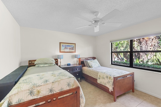 bedroom featuring light tile patterned floors, a ceiling fan, baseboards, and a textured ceiling