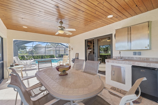 view of patio / terrace featuring glass enclosure, area for grilling, an outdoor pool, a ceiling fan, and a sink