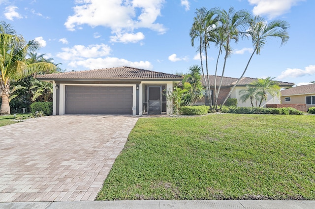 view of front of property featuring a front lawn, a tile roof, stucco siding, decorative driveway, and an attached garage