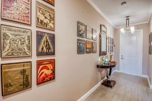 foyer featuring ornamental molding, an inviting chandelier, baseboards, and wood finished floors