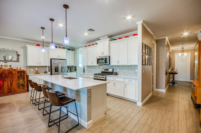 kitchen with visible vents, a breakfast bar area, stainless steel appliances, light countertops, and a sink