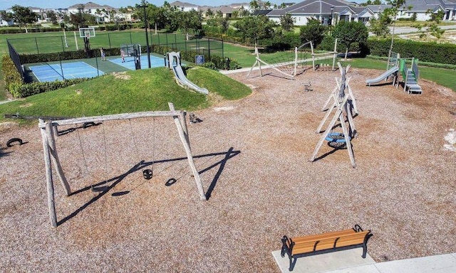 view of community featuring community basketball court, playground community, a lawn, and fence