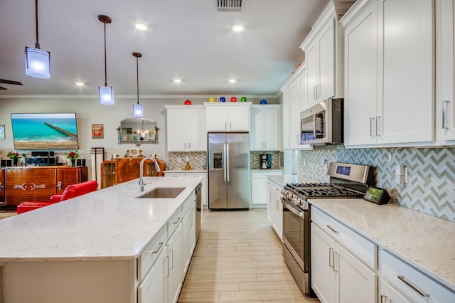 kitchen featuring appliances with stainless steel finishes, white cabinets, a sink, and ornamental molding