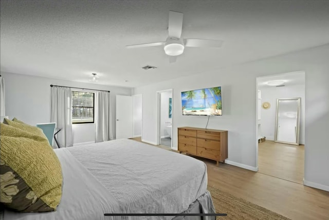 bedroom featuring baseboards, visible vents, ceiling fan, wood finished floors, and ensuite bathroom