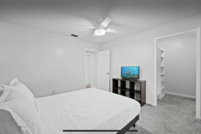 bedroom featuring a walk in closet, carpet flooring, ceiling fan, and baseboards