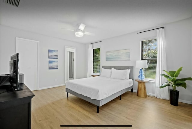 bedroom featuring multiple windows, light wood-type flooring, visible vents, and baseboards