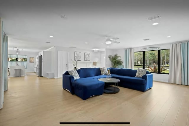 living area with light wood finished floors, visible vents, and recessed lighting