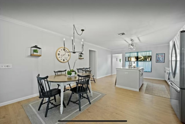 dining space with light wood-style floors, ornamental molding, and baseboards