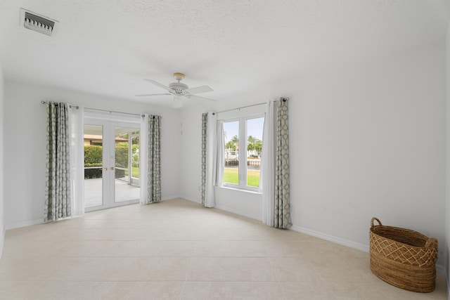 empty room with a wealth of natural light, visible vents, french doors, and a textured ceiling