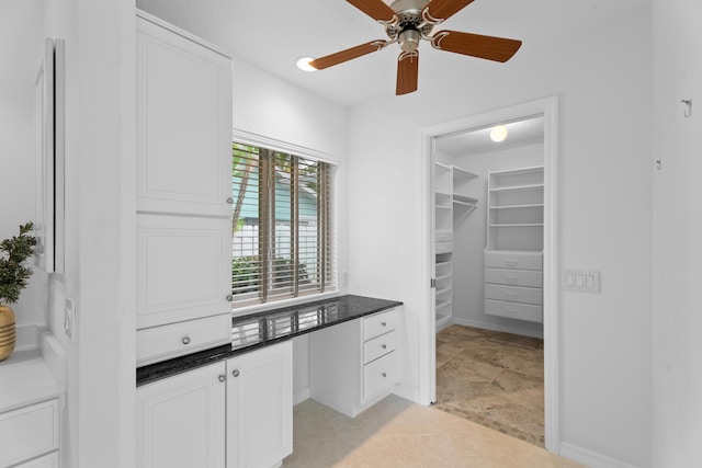 walk in closet featuring light tile patterned floors, a ceiling fan, and built in desk