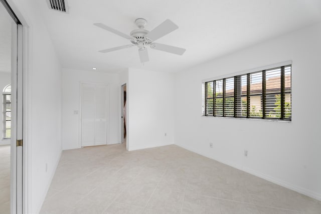 empty room with visible vents, baseboards, light tile patterned flooring, and a ceiling fan