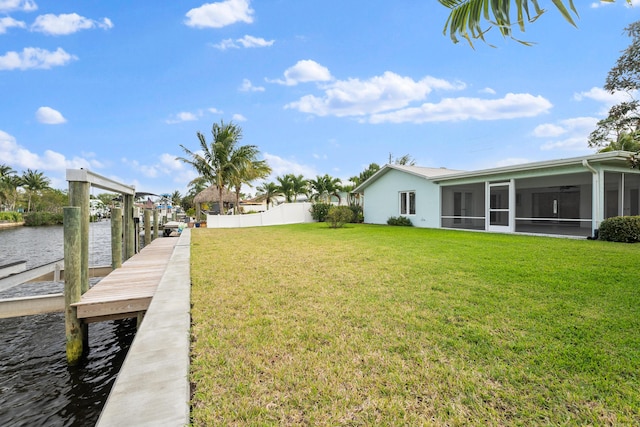 view of yard featuring a sunroom, a water view, a dock, and fence