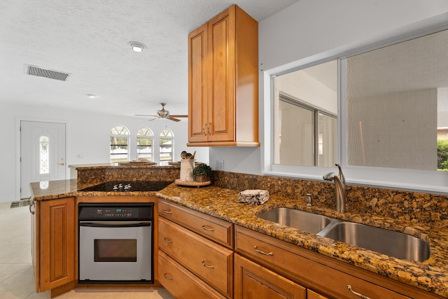 kitchen featuring oven, black electric stovetop, brown cabinets, and a sink