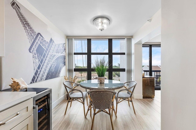 dining space featuring baseboards, wine cooler, and light wood-style floors