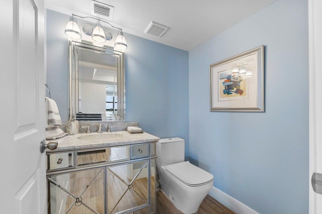 bathroom featuring visible vents, toilet, vanity, wood finished floors, and baseboards