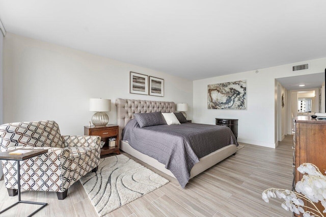 bedroom featuring light wood-style flooring, visible vents, and baseboards