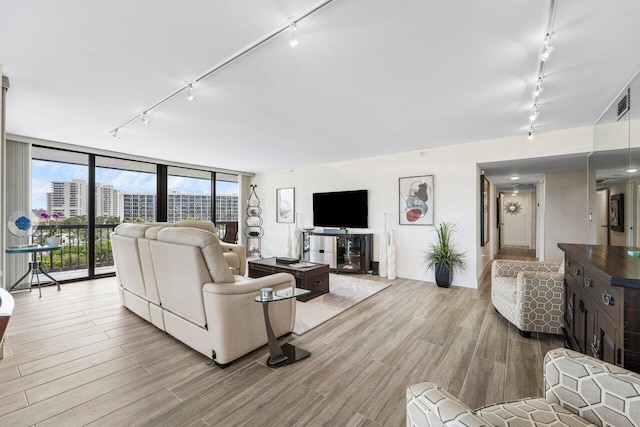 living room with a wall of windows, rail lighting, visible vents, and light wood finished floors